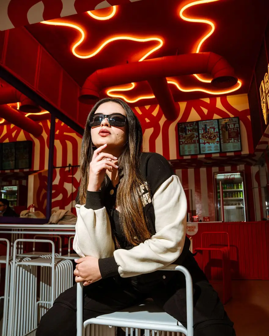 Model in sunglasses under the neon ceiling at Baba Doner