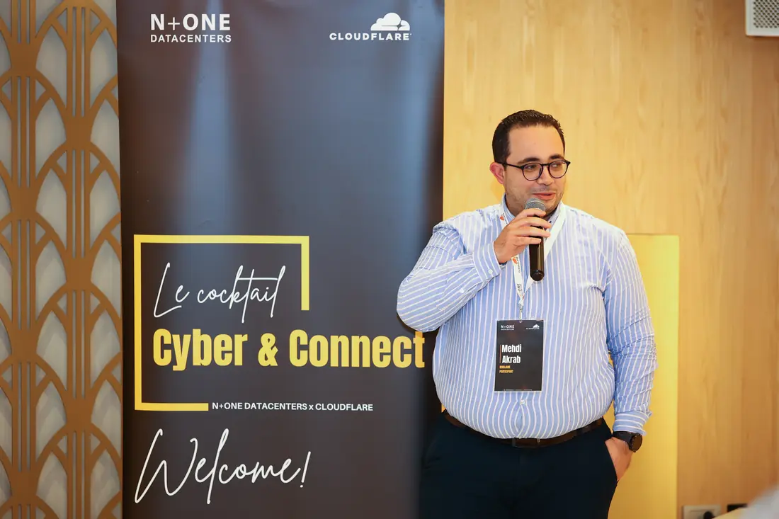 Speaker with a microphone beside the Cyber & Connect roll-up