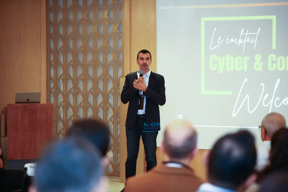 Host speaking in front of the Cyber & Connect welcome screen